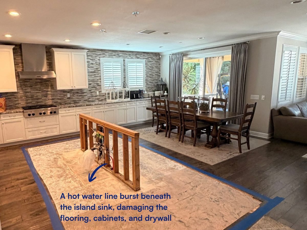 Open-plan kitchen with the floor around the island taped off where a hot water line burst beneath the island sink.